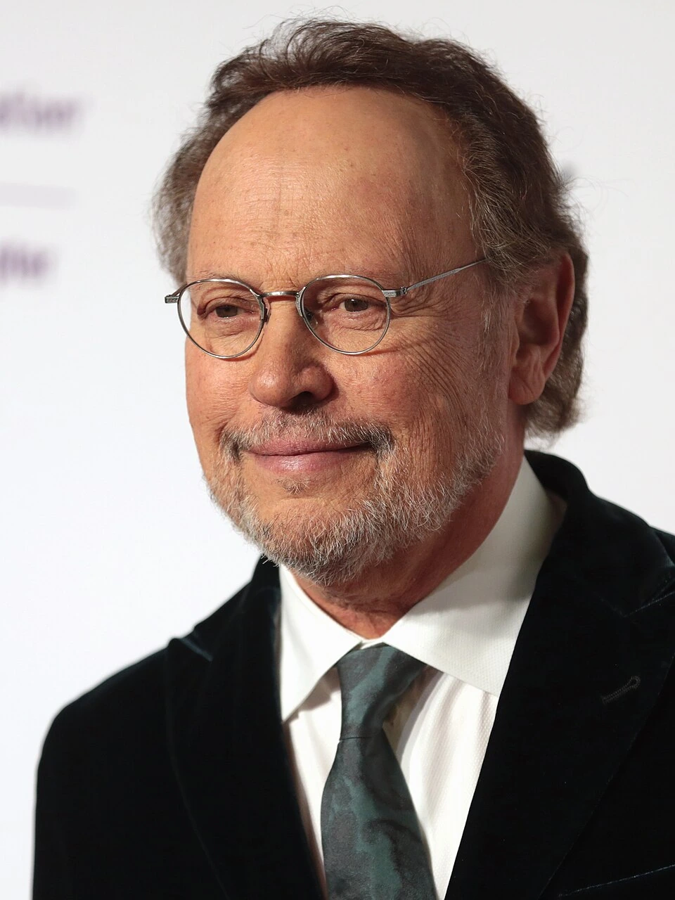 Billy Crystal smiling in a formal portrait at an event