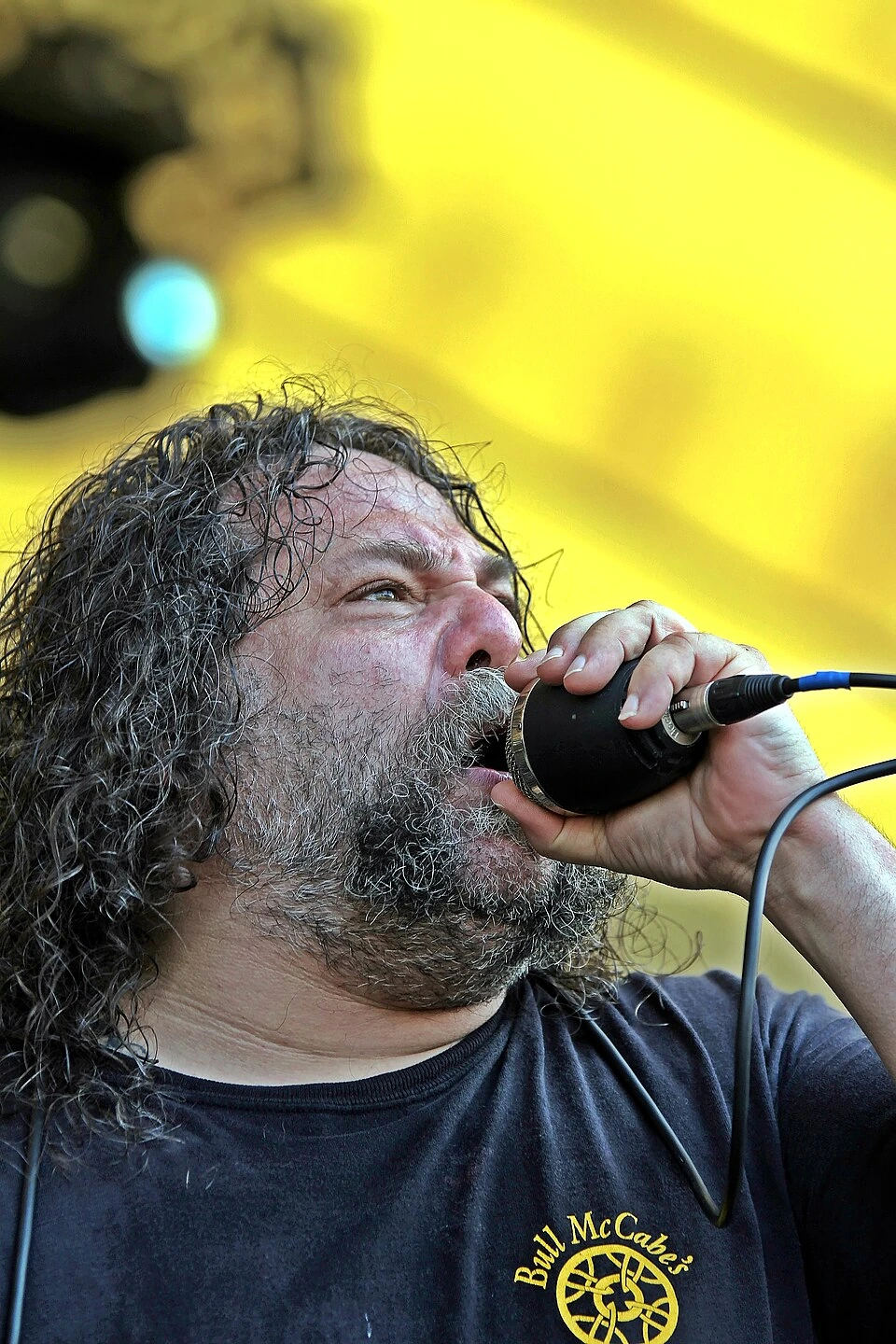 Billy Milano performing on stage with a microphone