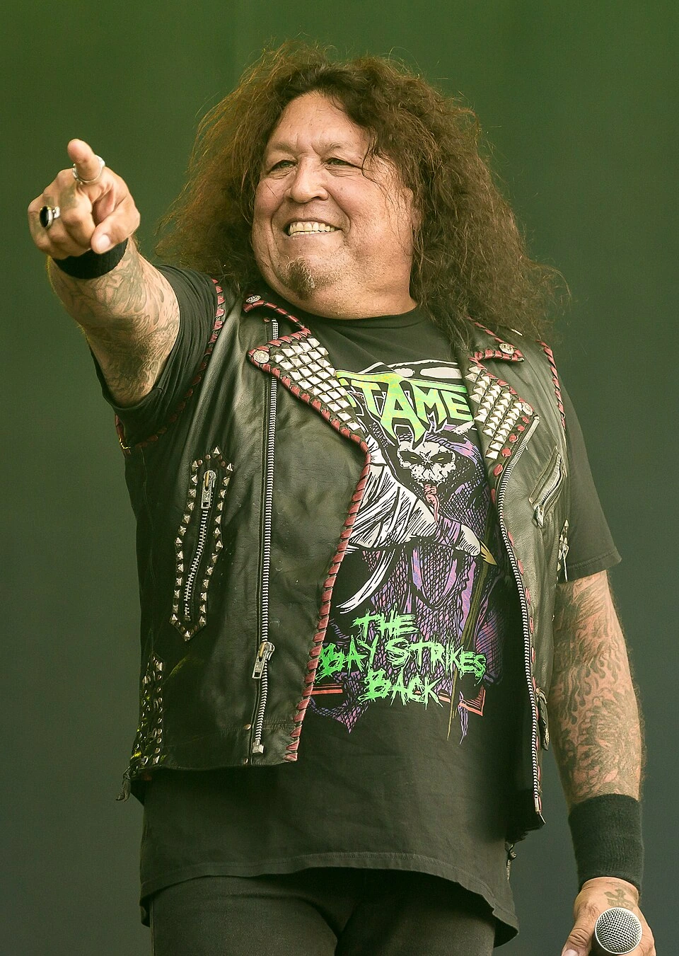 Chuck Billy of Testament performing on stage, pointing toward the crowd.